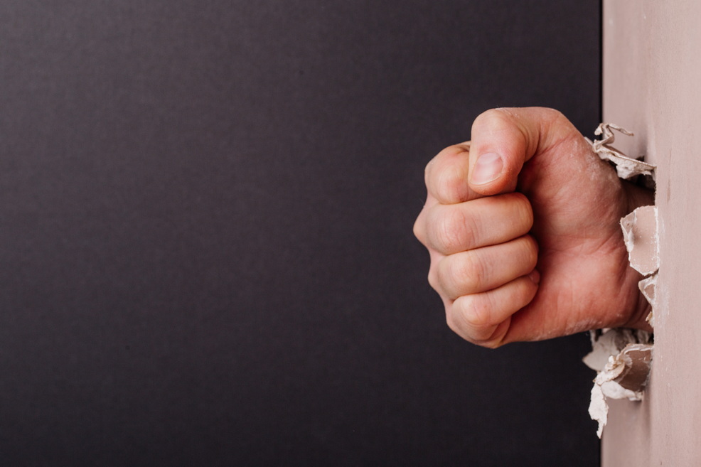 Faust schlägt durch die Wand.