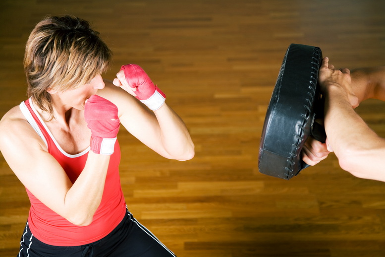Frau im Boxtraining boxt gegen eine Pratze