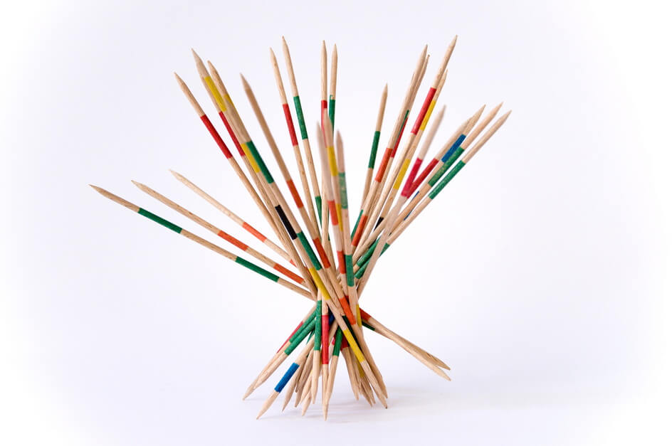 Selbstkontrolle unter Stress - Tempo rausnehmen. Mikadostäbchen, die aufgerichtet stehen, kurz bevor sie fallengelassen werden. Es ist allerdings keine Hand zu sehen, die die Stäbchen hält.